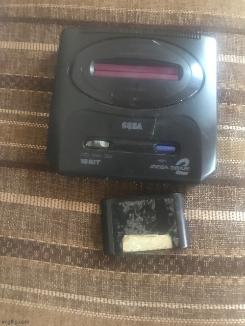My mom’s 30 year old Genesis along with something that I see as a super old cartridge, idk where the controllers are | made w/ Imgflip meme maker