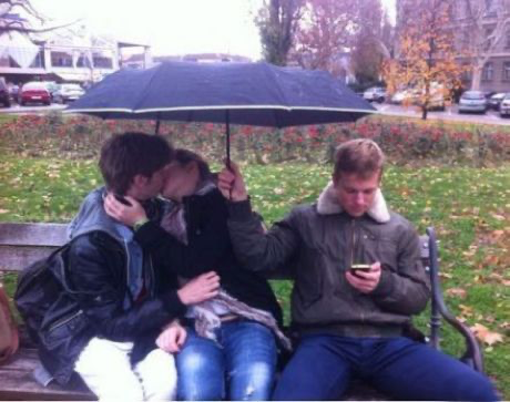 Guy on phone holding umbrella over kissing couple Blank Meme Template